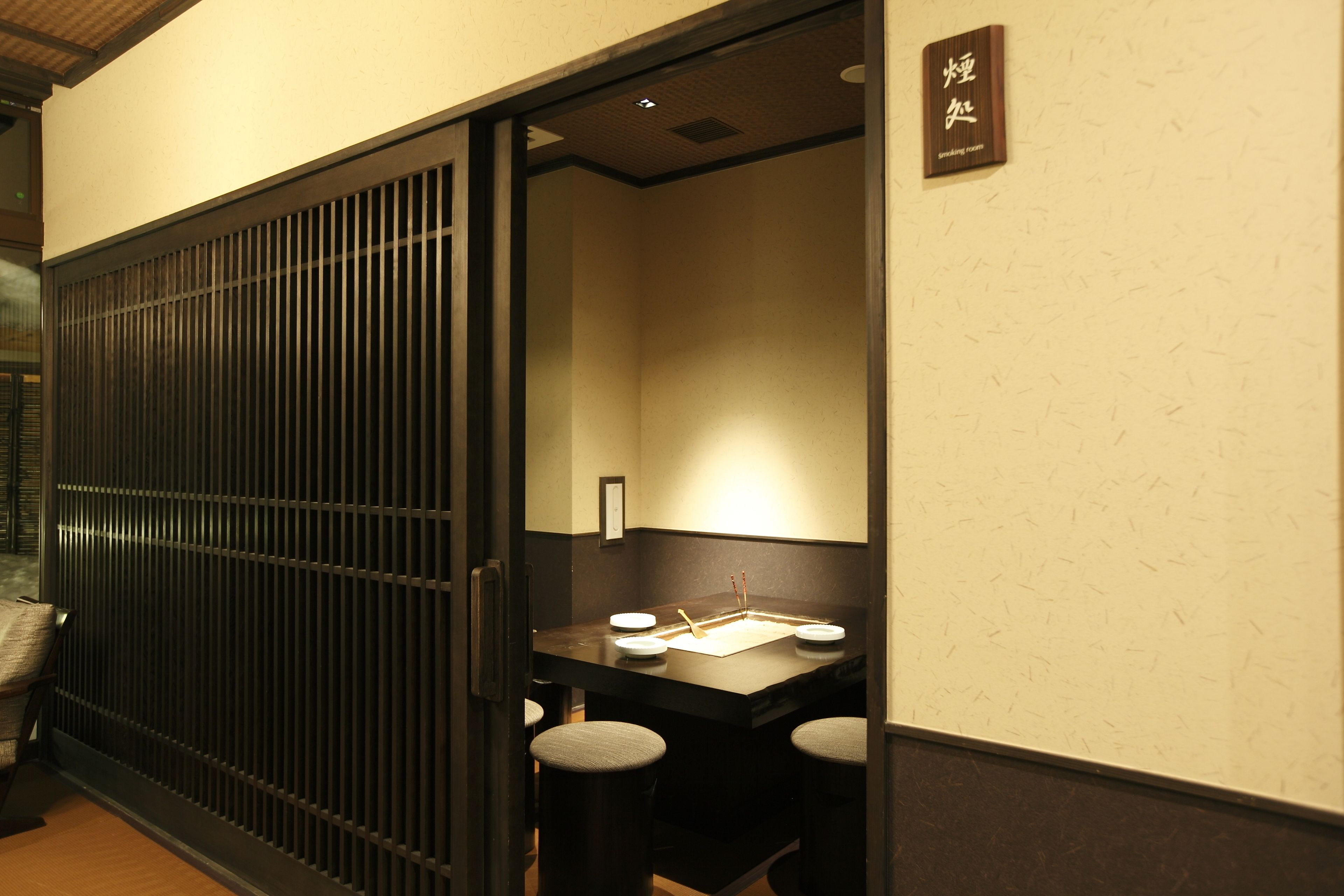 A traditional Japanese-style room with tatami flooring, a low table with a paper, and a shoji screen door.