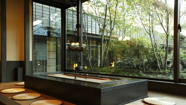 A modern interior with a large window, a black rectangular table, and woven mats on the floor. - Oyado Konoha (Kusatsu)
