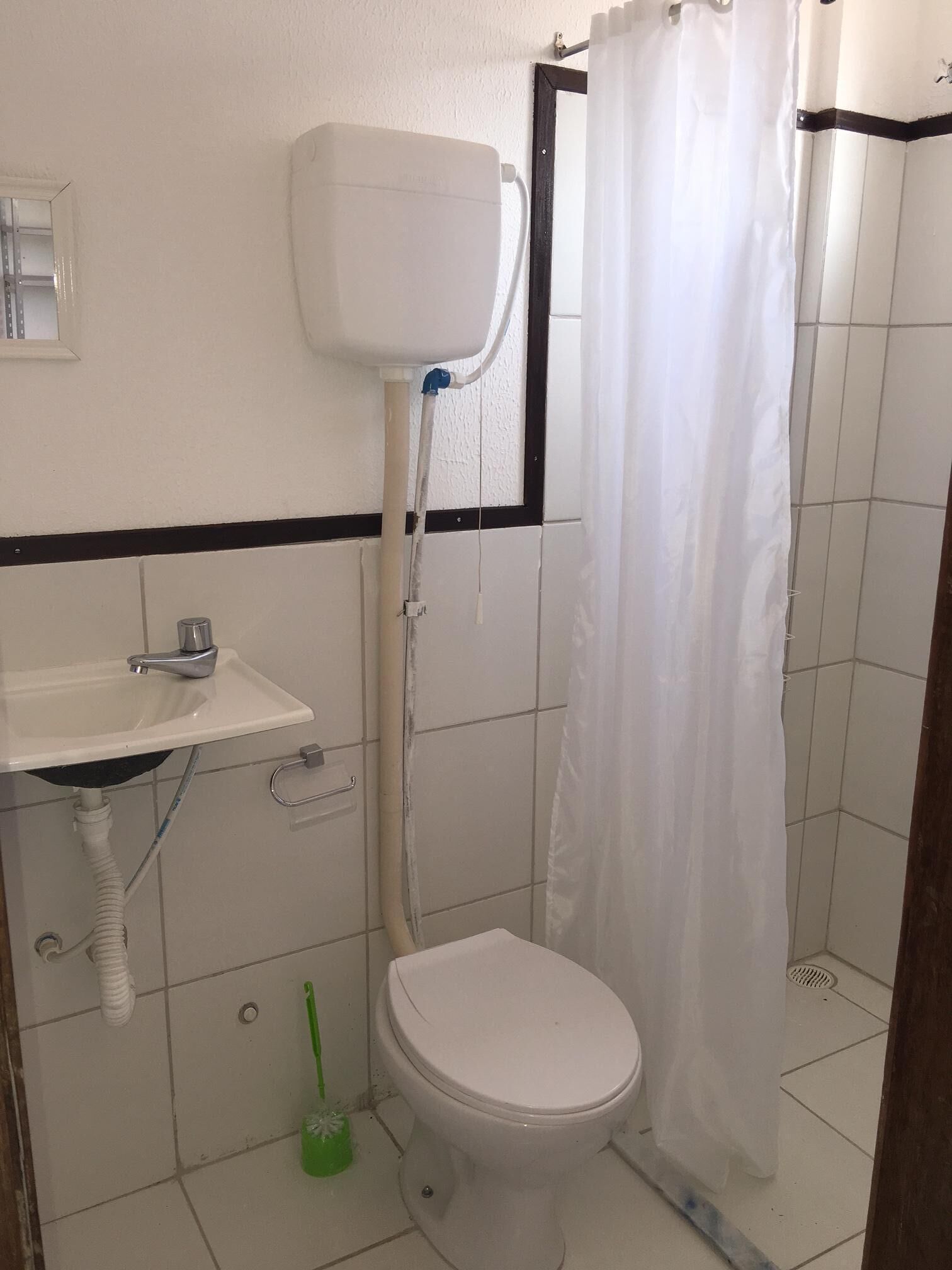 Une petite salle de bain avec des toilettes, un lavabo et un rideau de douche.