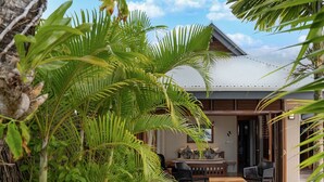 A wooden deck with a bench and chairs, surrounded by lush tropical plants. - All inclusive Beachfront Villa in Fiji! (Sigatoka)