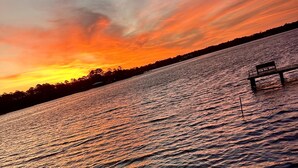Een zonsondergang boven het water, met een bankje aan de oever.