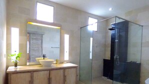 A modern bathroom with a glass-enclosed shower, a large mirror, and a wooden vanity. - Villa Mels (Jimbaran)