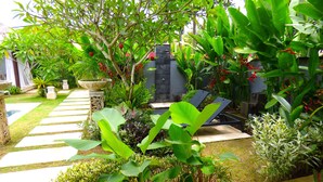 A garden with a stone pathway, a water feature, and a seating area with a table and chairs. - Villa Mels (Jimbaran)