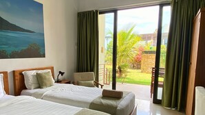 A hotel room with two beds, a desk, a chair, and a view of a garden and building through large windows. - The Happinezz Hills Hotel Karimunjawa (Karimun Jawa)