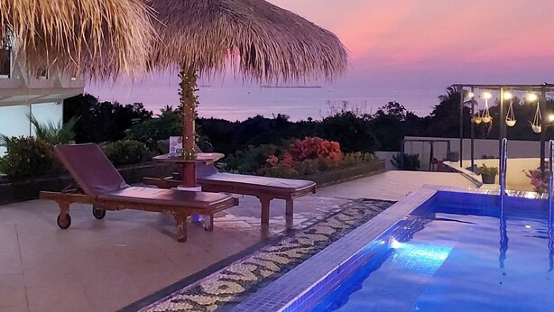 A poolside area with lounge chairs, a thatched umbrella, and a pool. - The Happinezz Hills Hotel Karimunjawa (Karimun Jawa)