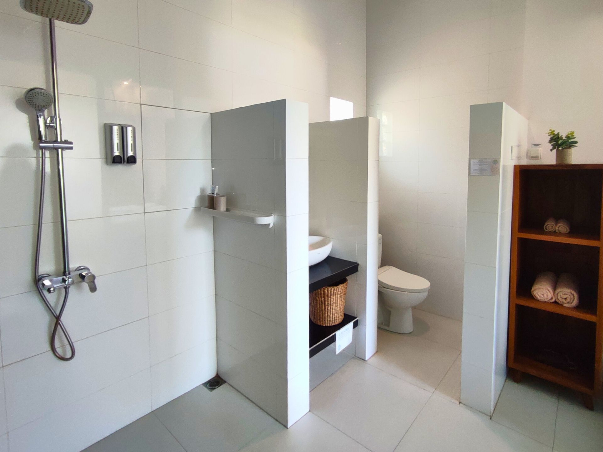 Une salle de bain moderne équipée d’une douche, de toilettes et d’une étagère où sont rangées les serviettes.
