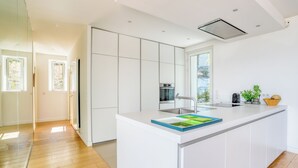 Een moderne keuken met witte kasten, een centraal eiland en een groot raam dat voor natuurlijk licht zorgt.