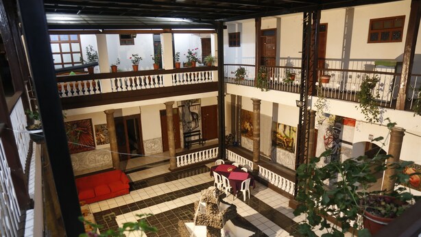 A multi-level courtyard with tiled floors, a red sofa, and potted plants. - Casa de las Culturas San Marcos (Quito)