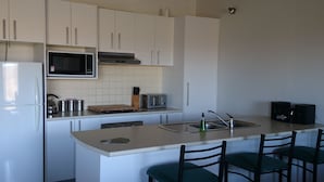 A modern kitchen with white cabinets, a microwave, a toaster, and a sink. - Elm Riverside Accommodation Merrijig (Merrijig)
