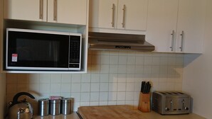 A kitchen with white cabinets, a stainless steel oven, a microwave, a toaster, and a coffee maker. - Elm Riverside Accommodation Merrijig (Merrijig)