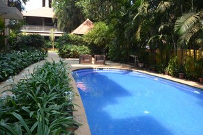 A swimming pool surrounded by lush greenery, with a covered structure in the background. - Tangerine Boutique Resort (Calangute)