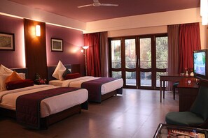 A hotel room with two beds, a desk, a chair, a television, and large windows with curtains. - Tangerine Boutique Resort (Calangute)