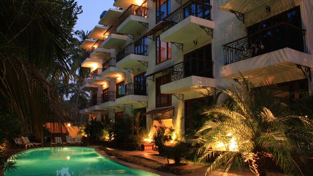 Un hotel con varios balcones, piscina y palmeras.