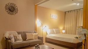 A hotel room with a bed, a sofa, a coffee table, and a lamp. - Uptown BGC near St. Luke's (Taguig)