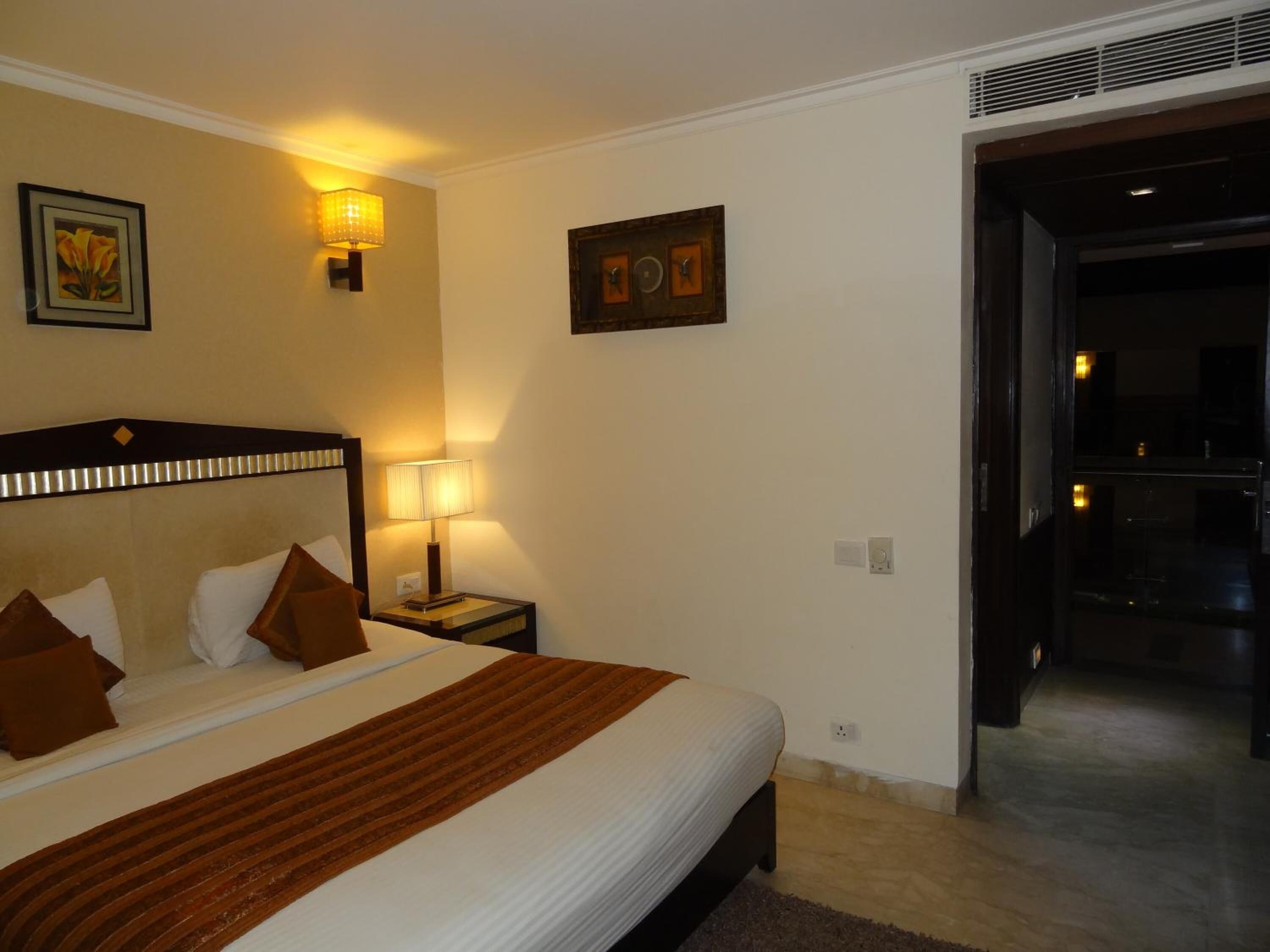 A hotel room with a large bed, two bedside lamps, a painting on the wall, and a door leading to a balcony.