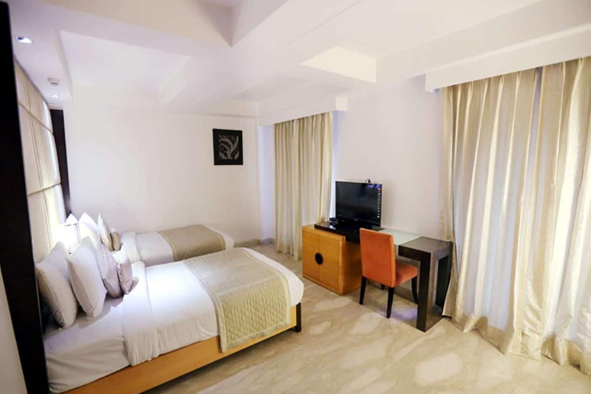 A hotel room with a bed, a desk with a chair, a television, and curtains.