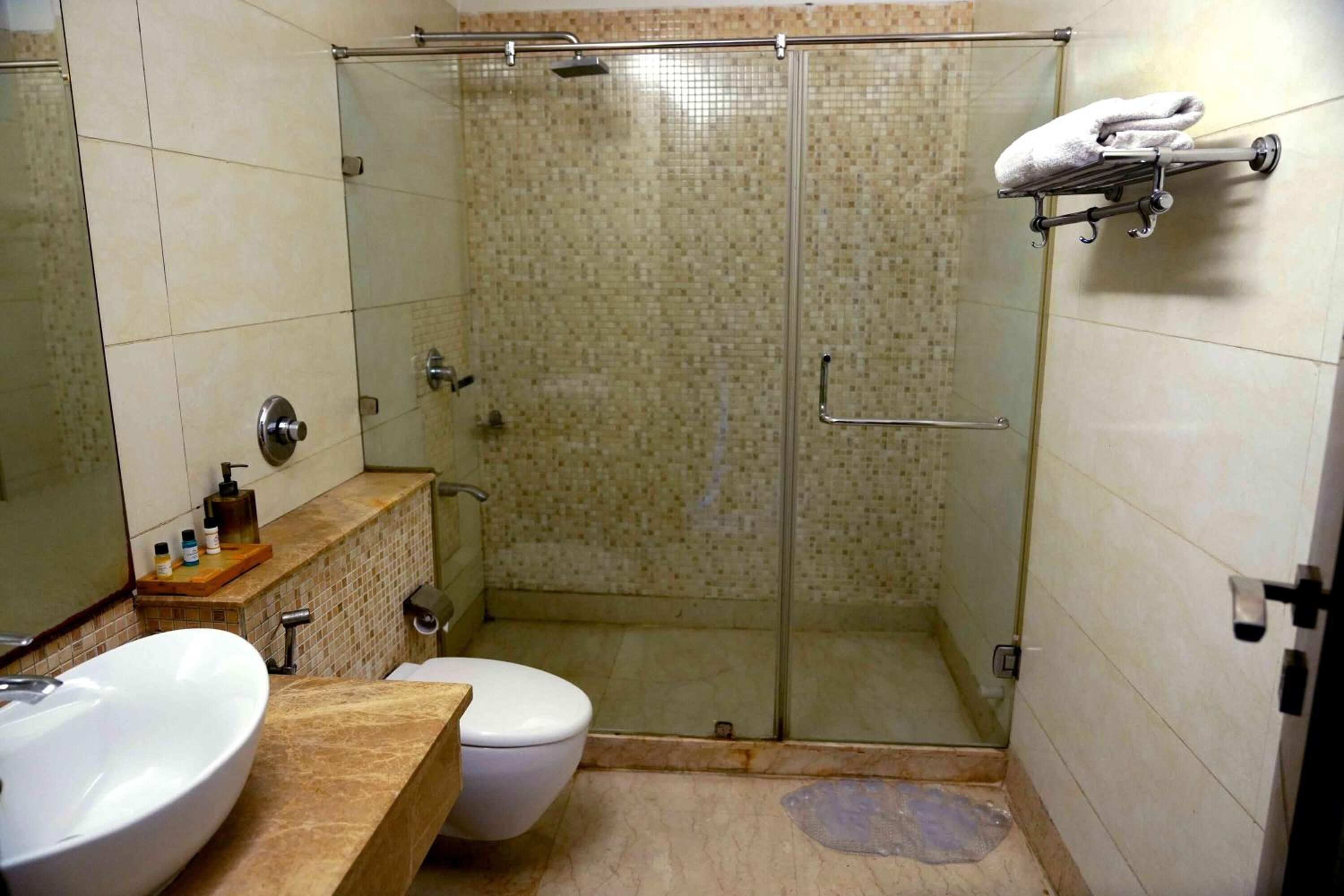 A bathroom with a glass shower enclosure, a sink, a toilet, and a towel rack.