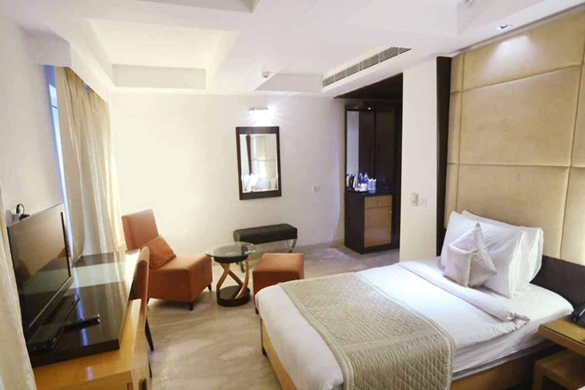 A hotel room with a bed, a TV, a desk, and a chair.