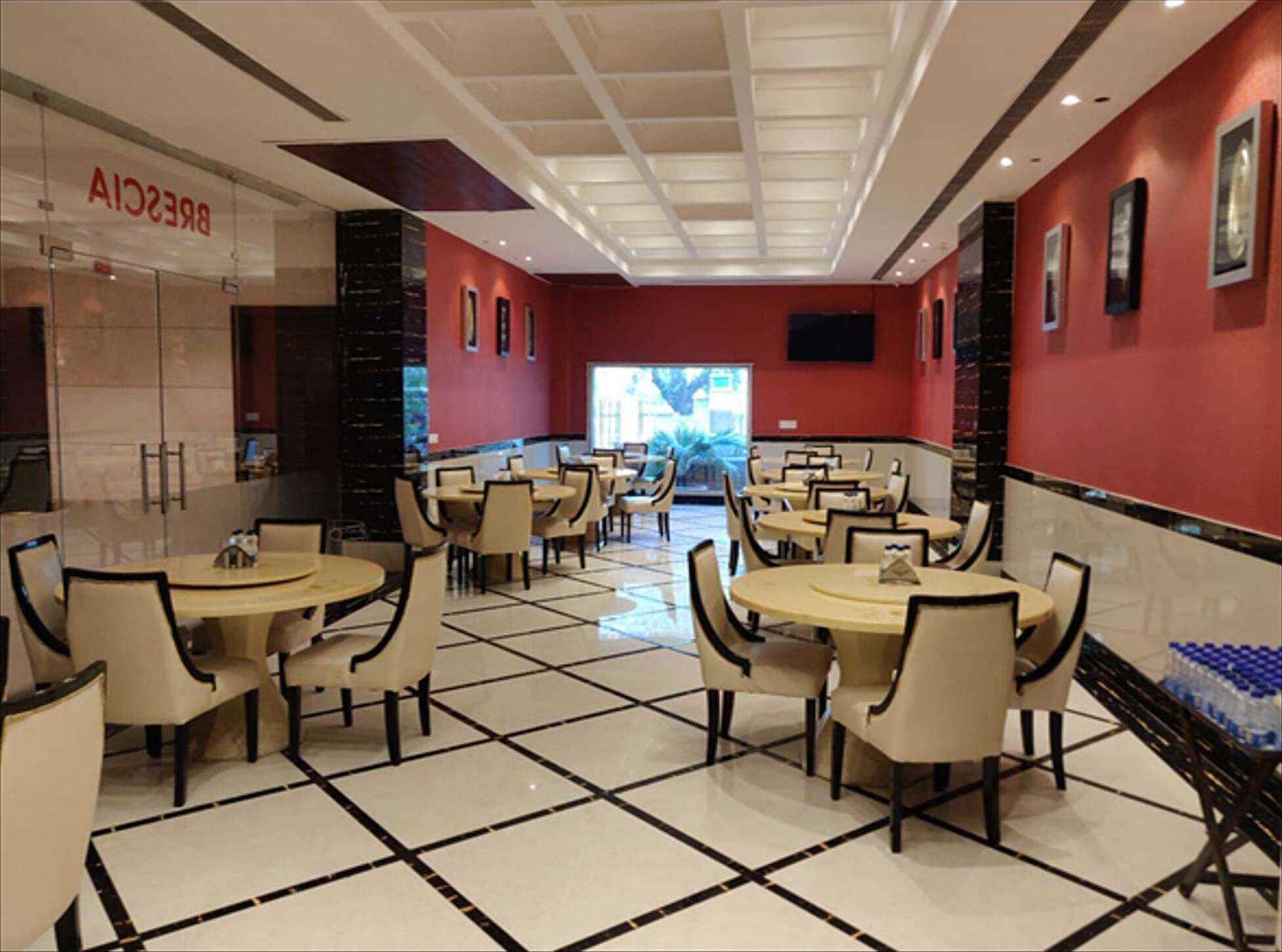 A restaurant with round tables and chairs, a tiled floor, and red walls.