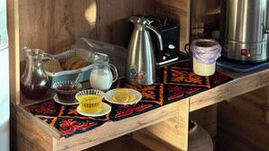 Uma cozinha com prateleiras de madeira, uma cafeteira, uma chaleira e uma caixa de chá Teatone.