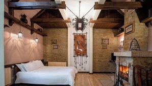 Quarto com teto de madeira, lareira e cama com roupa de cama branca.