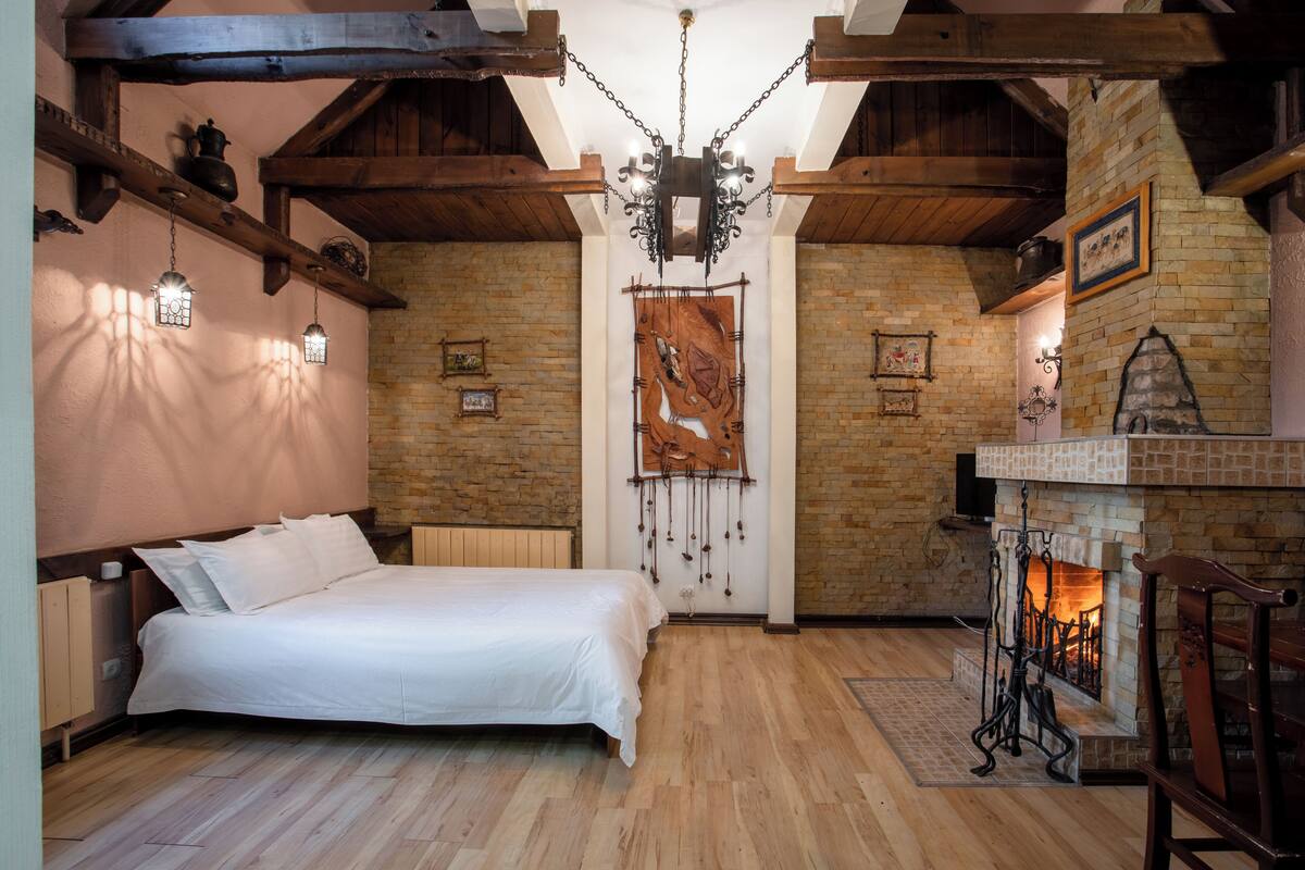 Una camera da letto con soffitto in legno, camino e letto con biancheria bianca.