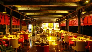Een restaurant met rode en witte stoelen, een gepolijste vloer en een bar op de achtergrond.