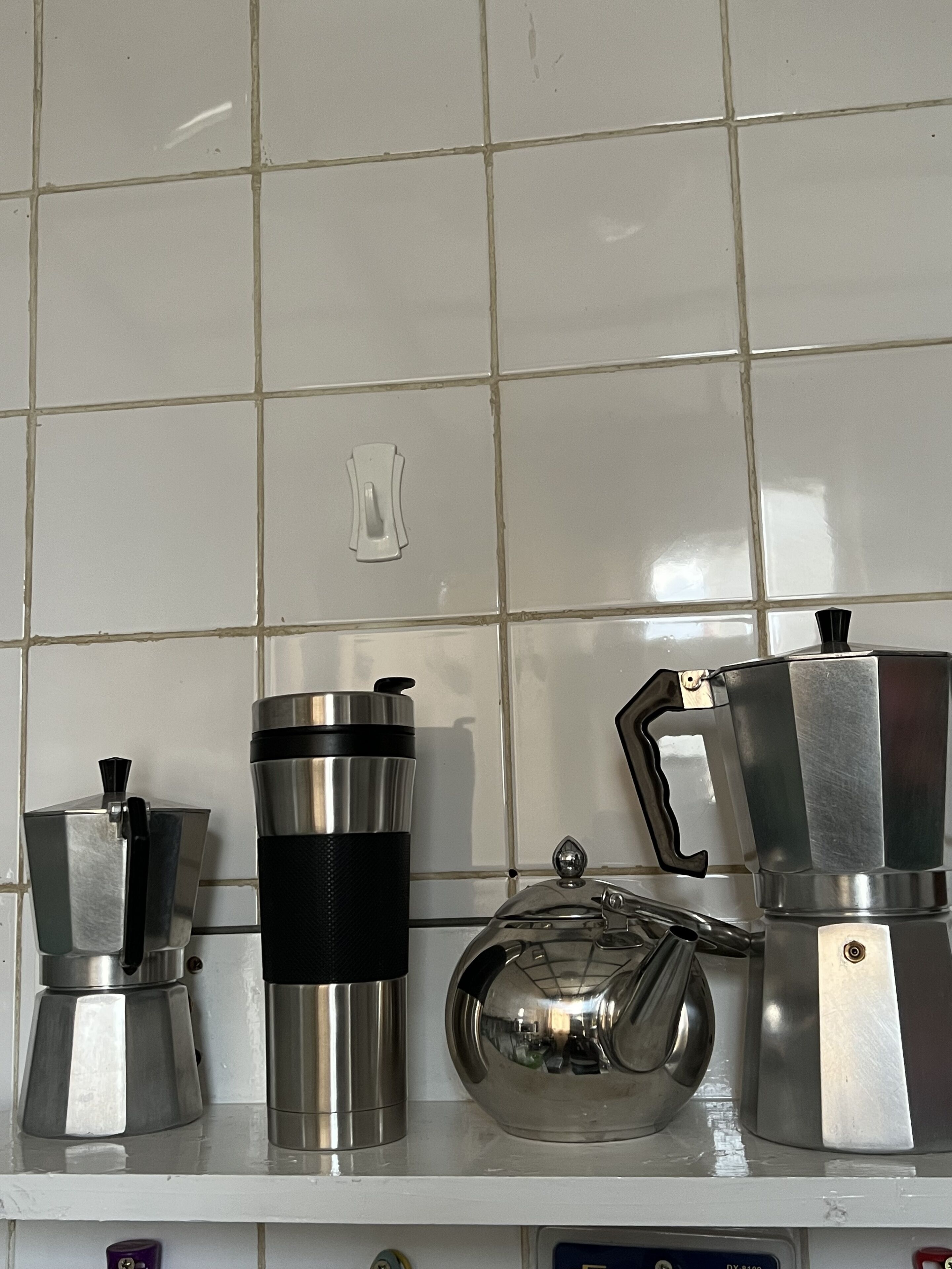 A kitchen counter with a coffee maker, a thermos, and a teapot.