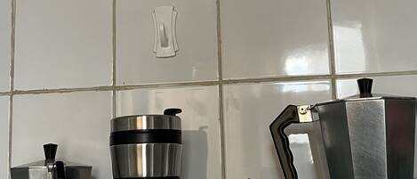 A kitchen counter with a coffee maker, a thermos, and a teapot.
