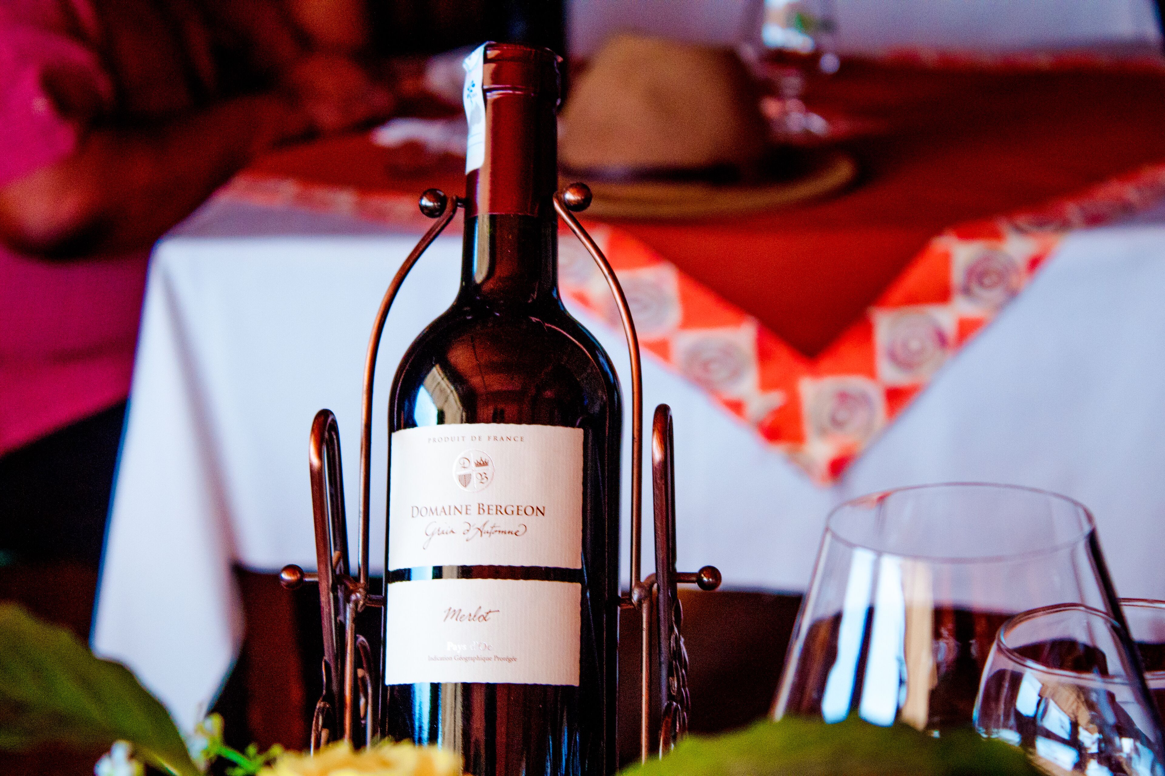 Una botella de vino Domaine Bergeon con etiqueta, sobre una mesa con mantel rojo.
