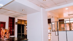 Un vestíbulo de hotel con un reloj, una escultura de madera y un mostrador de recepción.