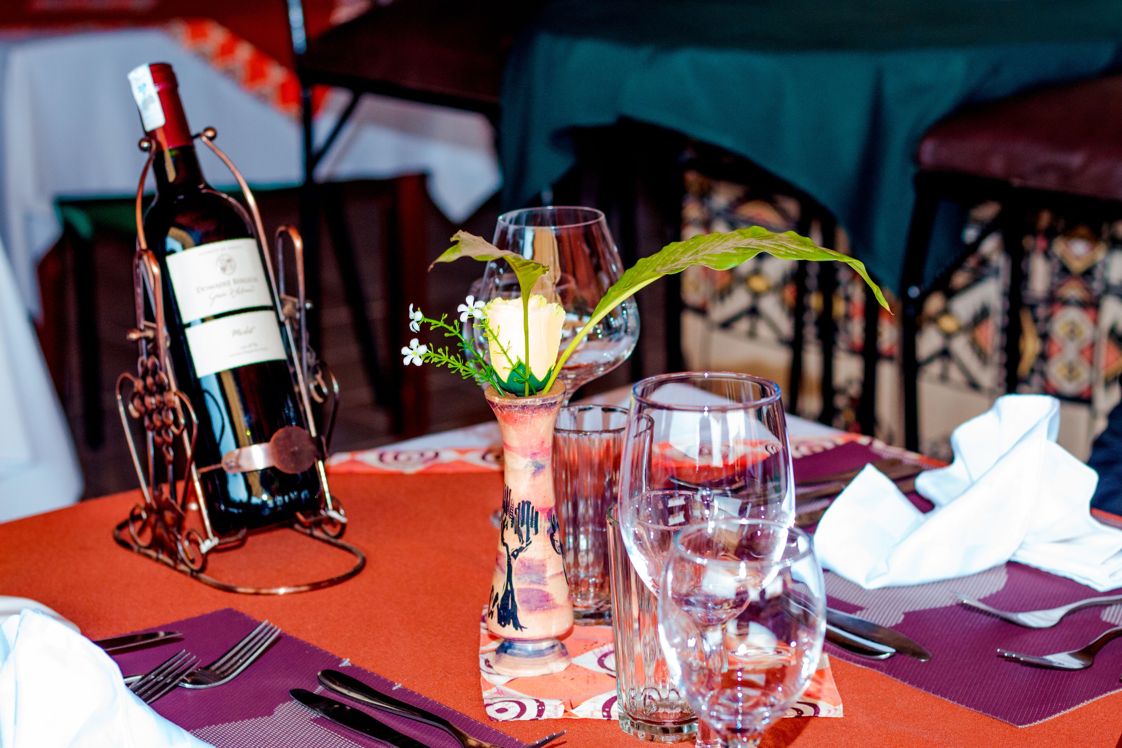 A table set with wine bottles, glasses, and a decorative vase with flowers.