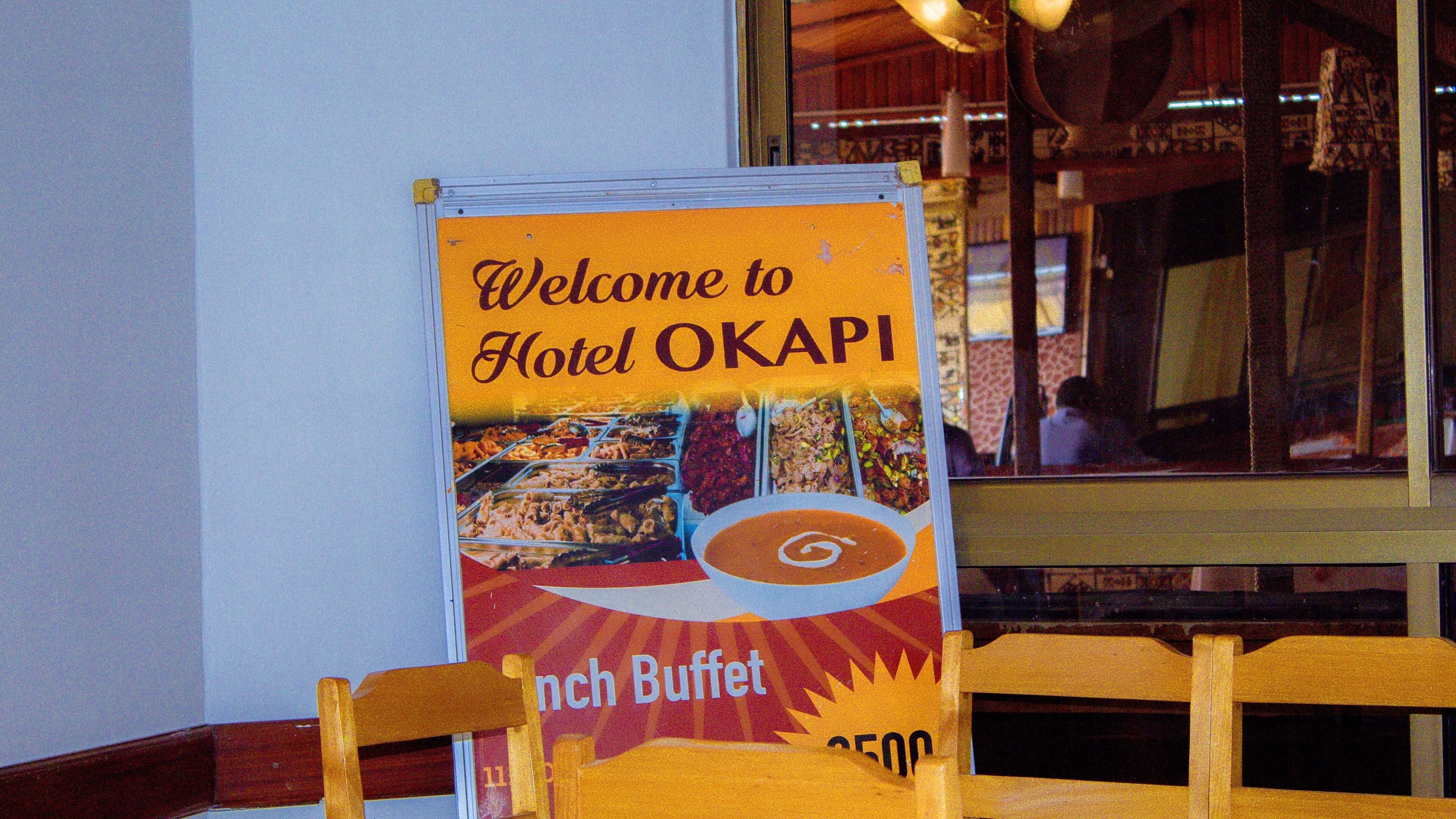 A signboard with a welcome message for Hotel OKAPI, indicating a buffet.