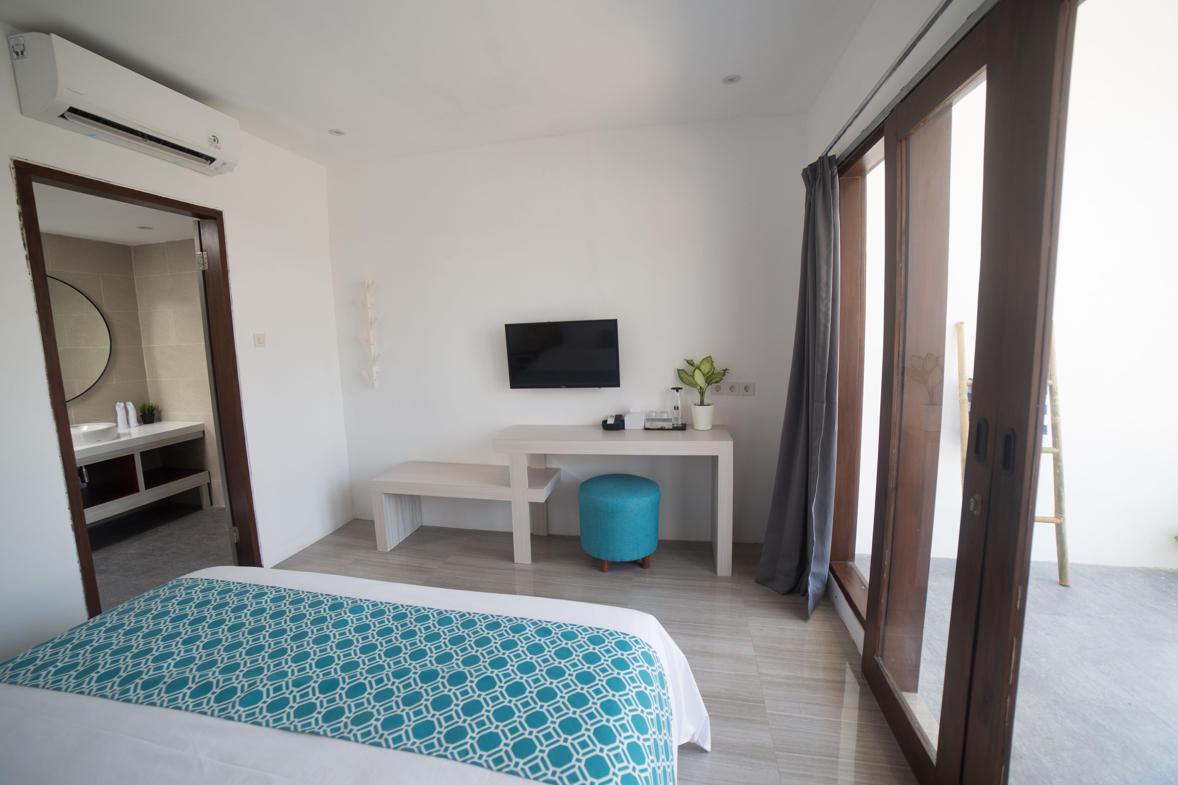 A hotel room with a bed, a desk, a television, and a large window.