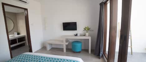 Una habitación de hotel con cama, escritorio, televisión y un amplio ventanal.