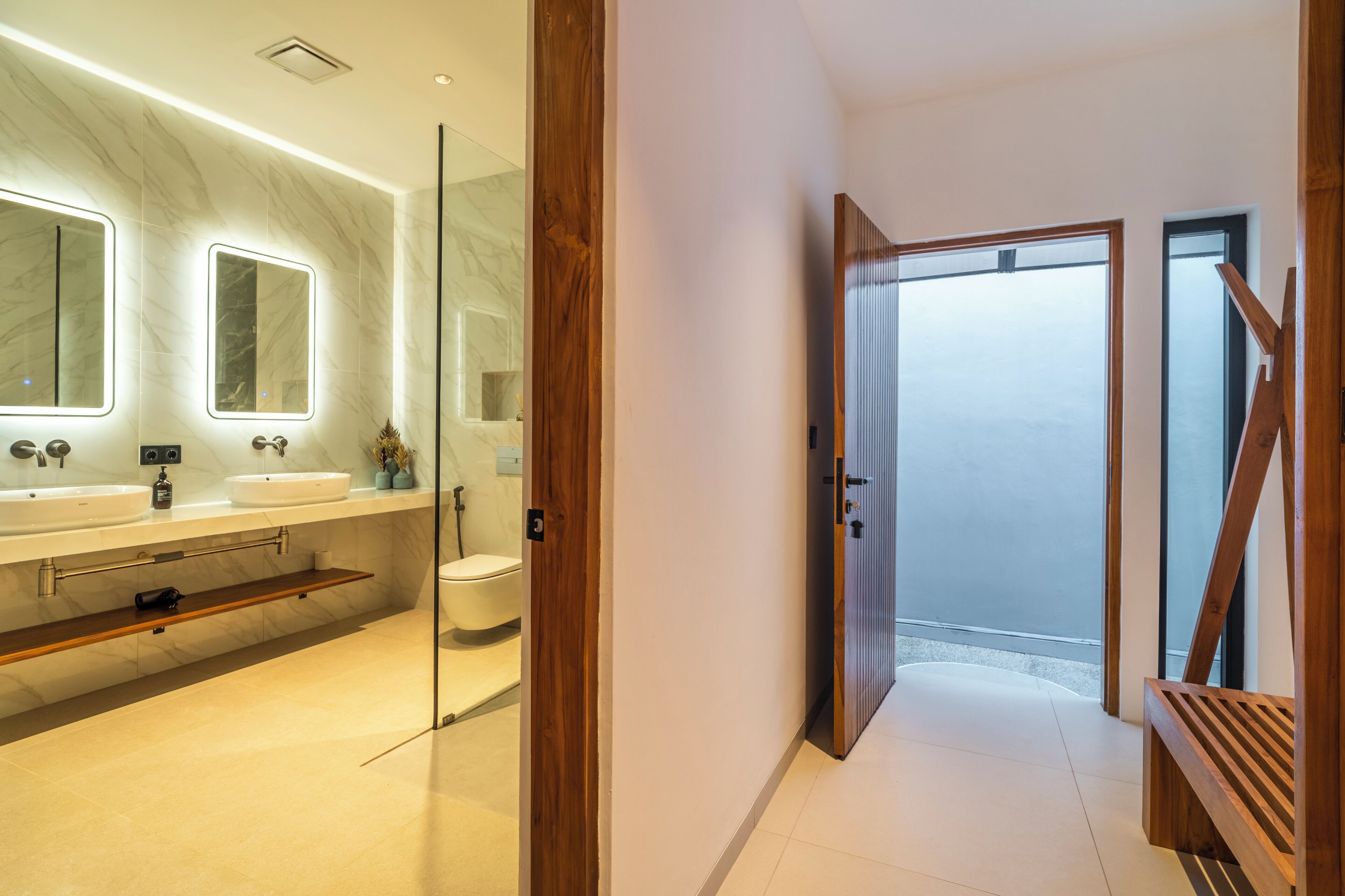 A modern bathroom with two sinks, a toilet, and a glass shower enclosure.