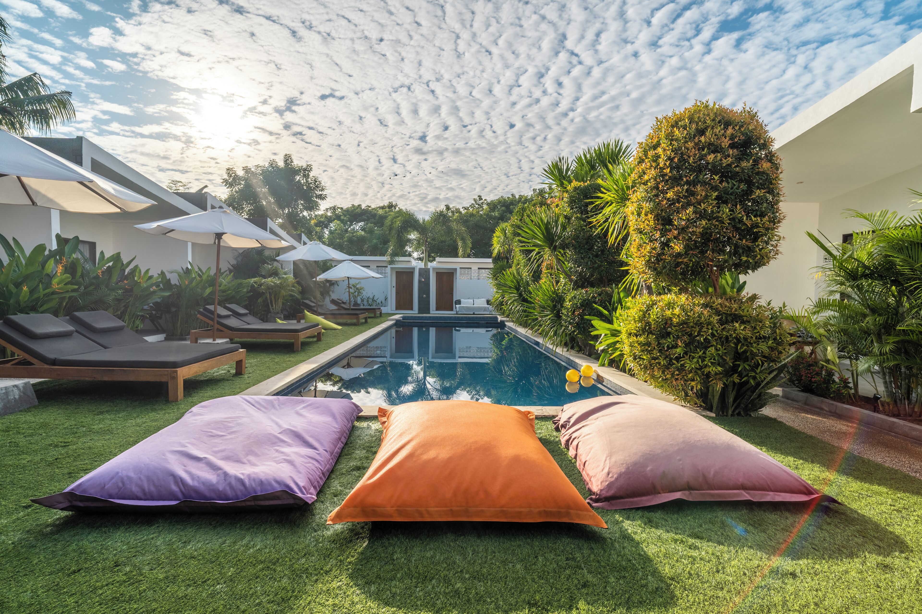 A pool area with artificial grass, lounge chairs, and umbrellas.