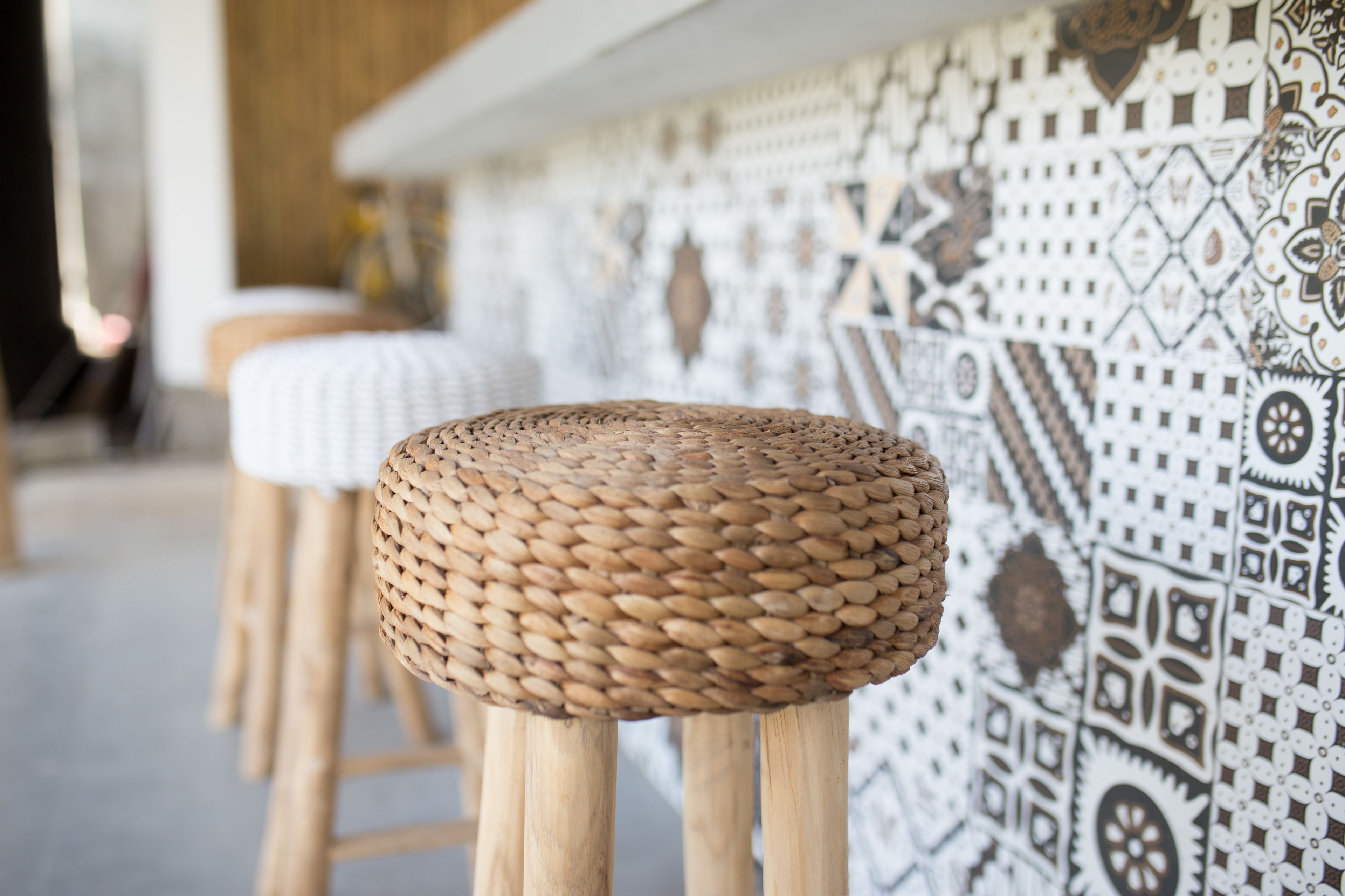 A bar area with a patterned wall and a woven stool.