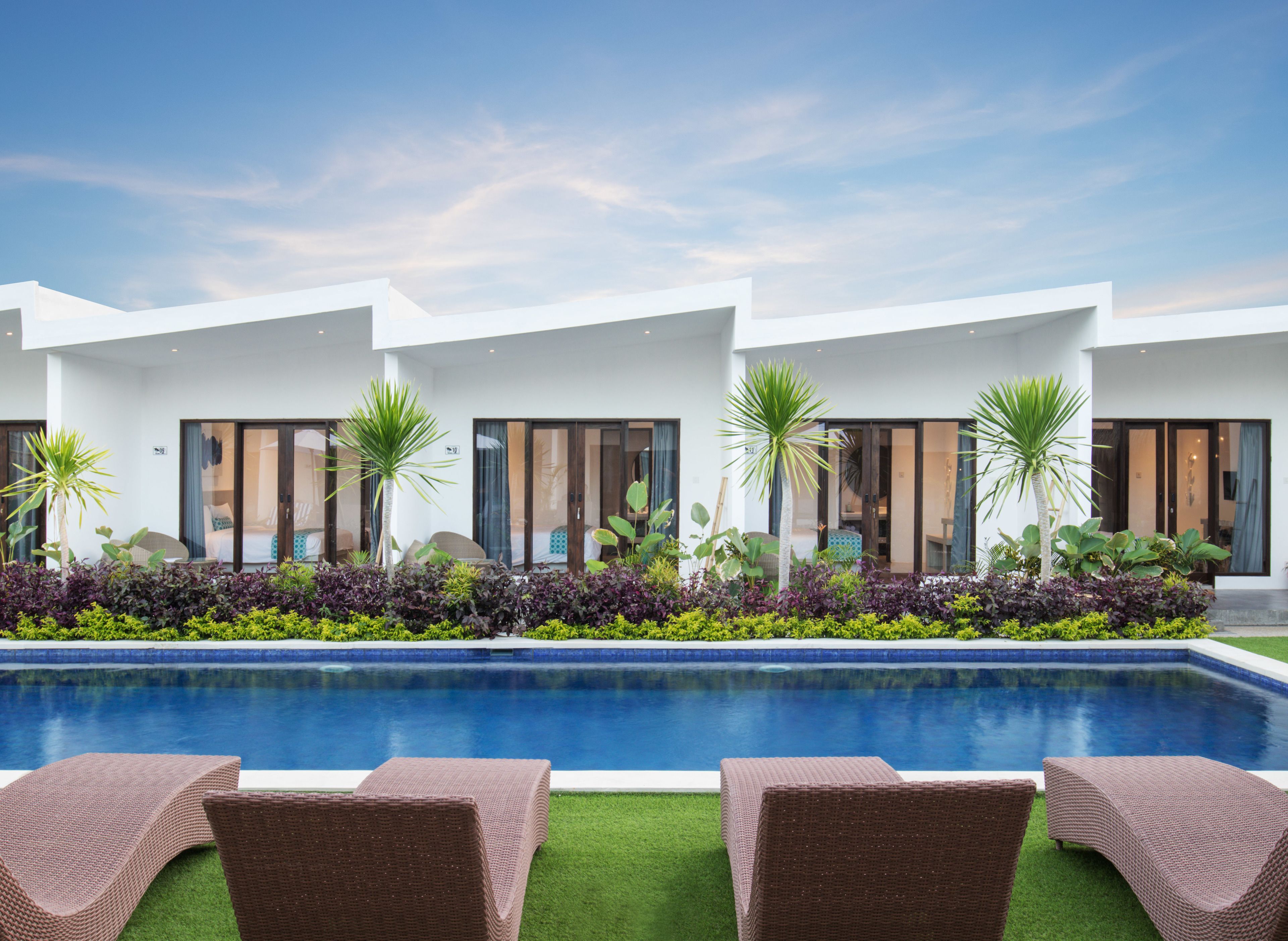 Un hôtel moderne doté d’une piscine, de chaises longues et d’un jardin bien entretenu.