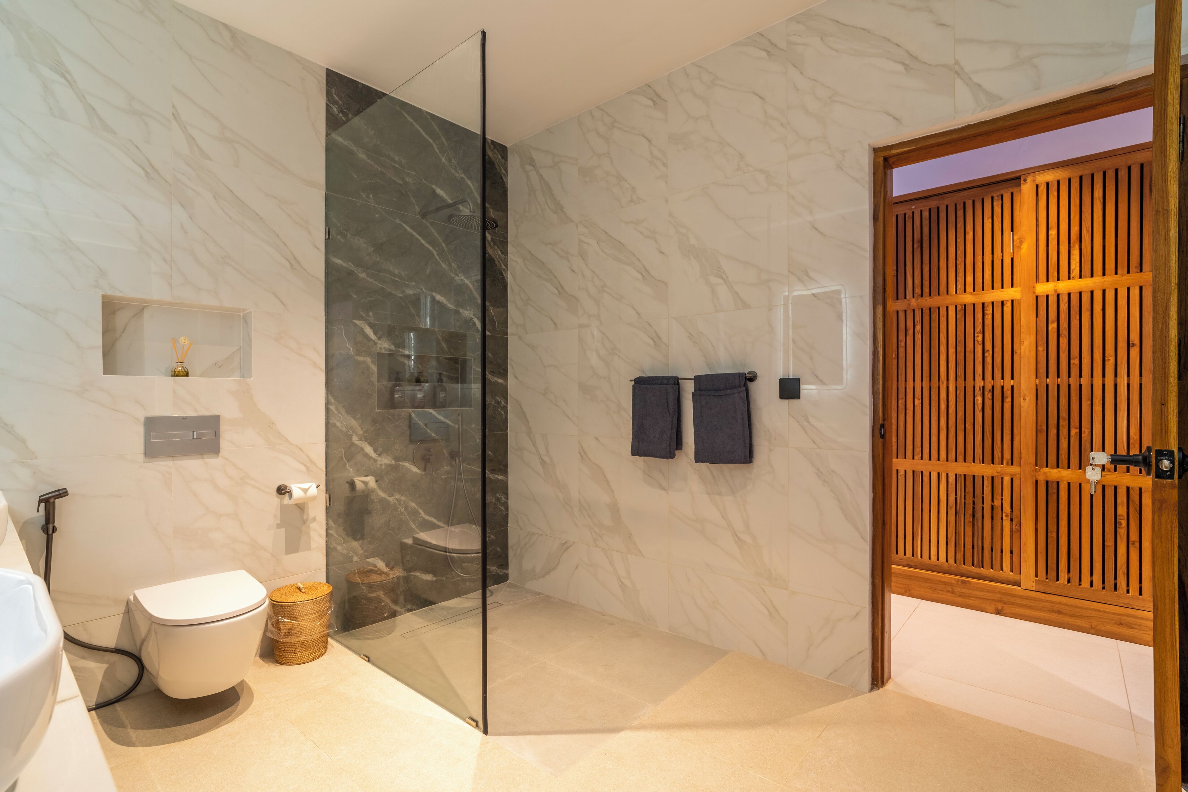Un baño moderno con cabina de ducha de vidrio, inodoro y puerta de madera.