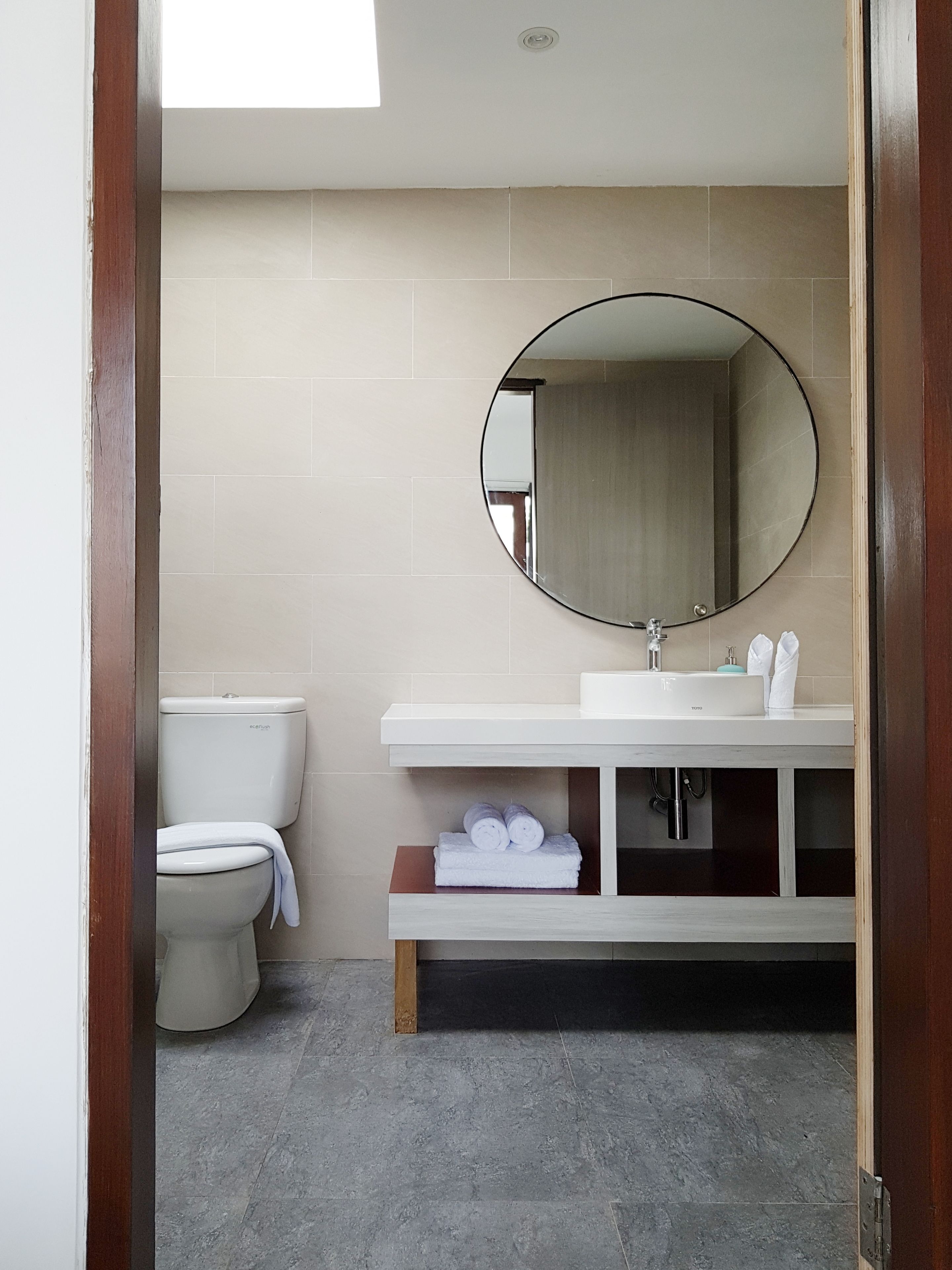 Un baño moderno con inodoro, lavabo y espejo.