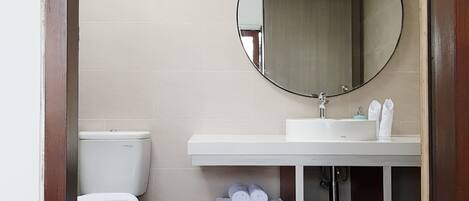Un baño moderno con inodoro, lavabo y espejo.
