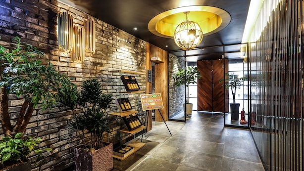 A modern lobby with a brick wall, wooden accents, and a variety of plants. - Jeonju Mari Hotel Terminal Store (Jeonju)