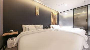 Ein modernes Hotelzimmer mit einem großen Bett, einem Nachttisch mit Taschentuchbox und einem Beistelltisch ebenfalls mit Taschentuchbox und Taschentüchern.