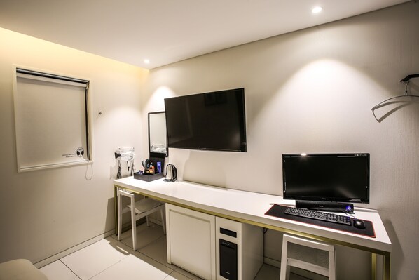 A modern hotel room with a white desk, two monitors, a keyboard, and a coffee machine. - Jeonju Mari Hotel Terminal Store (Jeonju)