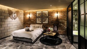 A modern bedroom with a brick wall, a large bed, a desk, and a view through a sliding door. - Jeonju Mari Hotel Terminal Store (Jeonju)