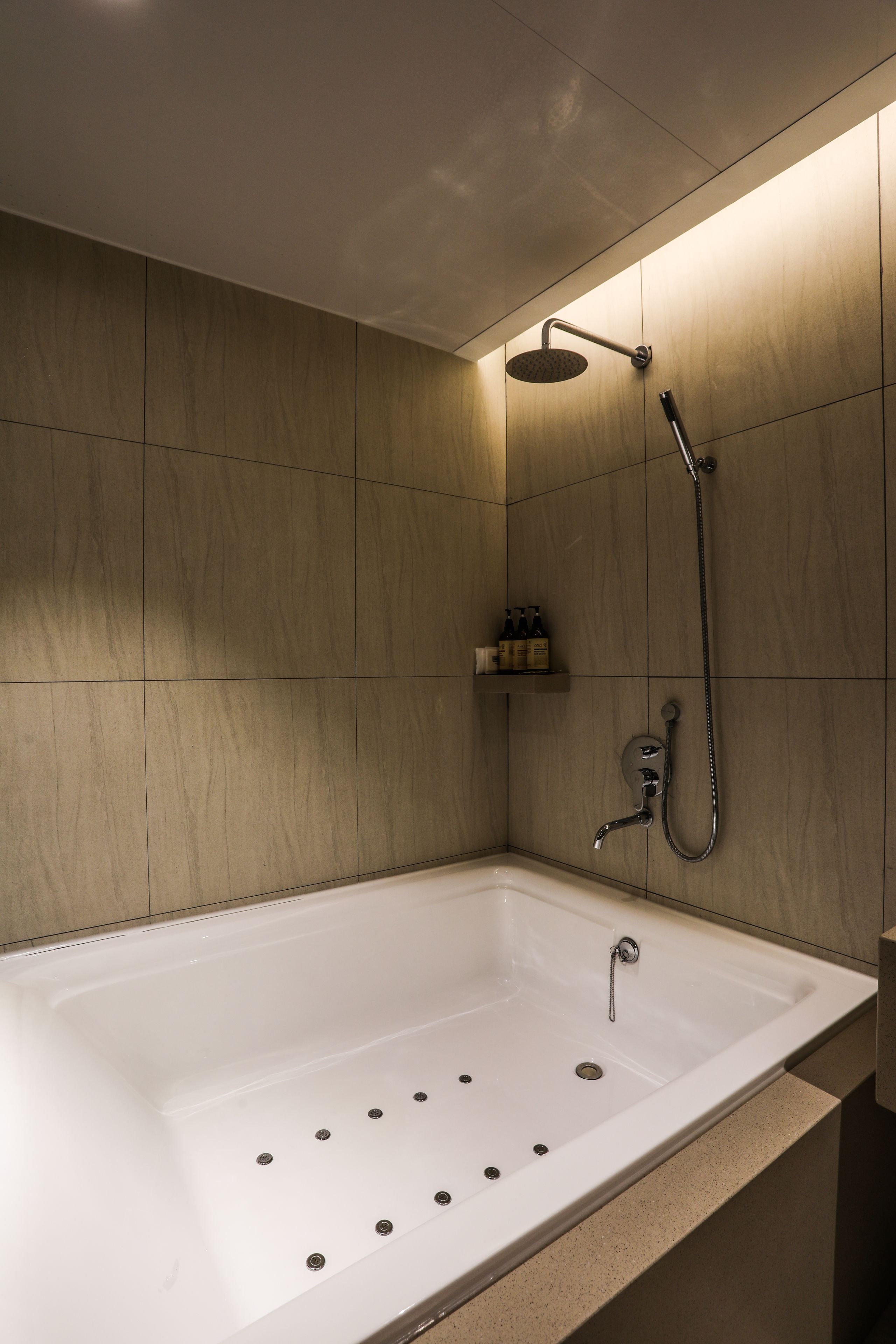 Un baño moderno con una bañera independiente, un cabezal de ducha manual y un grifo instalado en la pared.