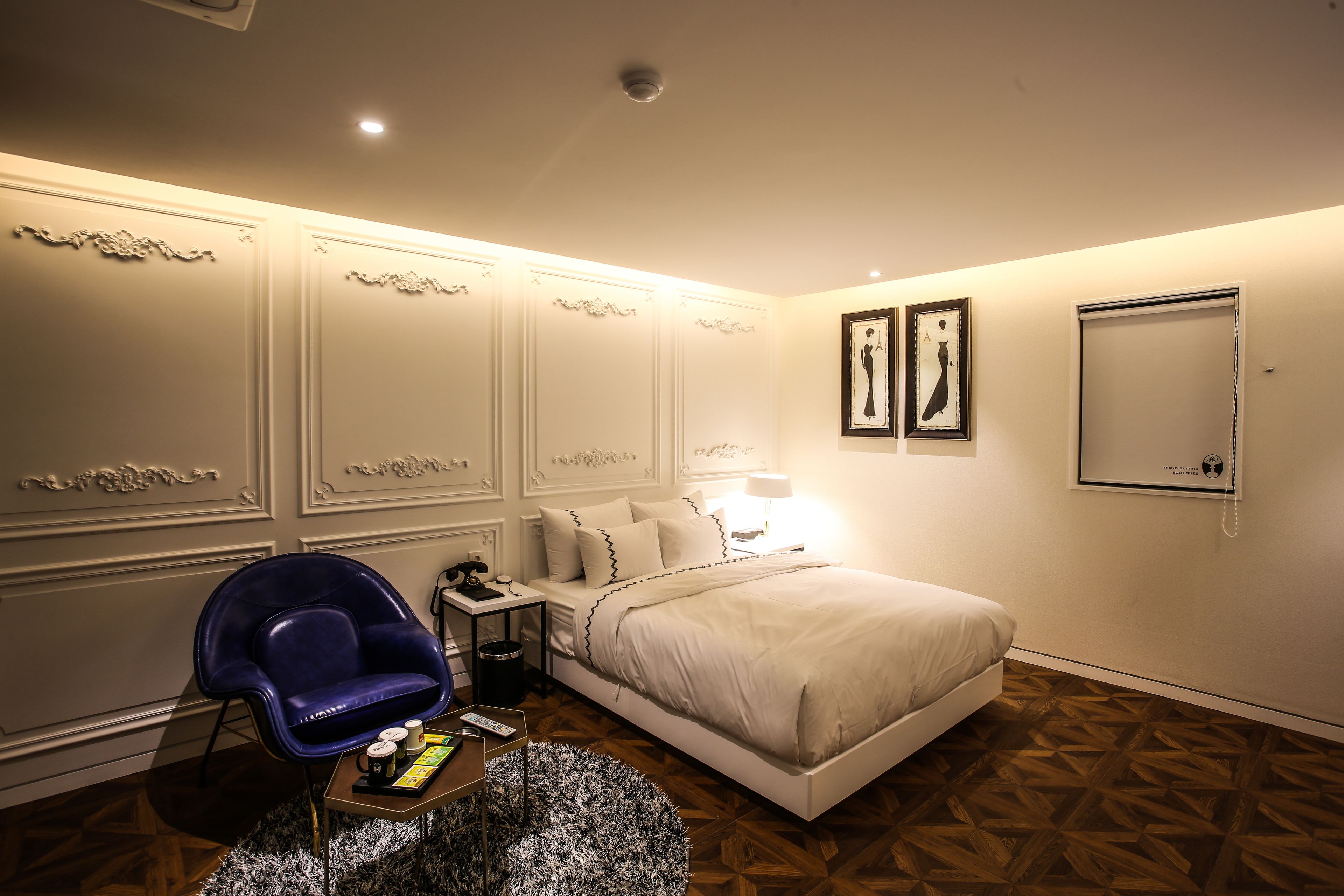 A bedroom with a bed, a chair, a nightstand, and a lamp.