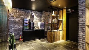 A modern lobby with a brick wall, a reception desk, a digital clock, and a fire extinguisher. - Jeonju Mari Hotel Terminal Store (Jeonju)