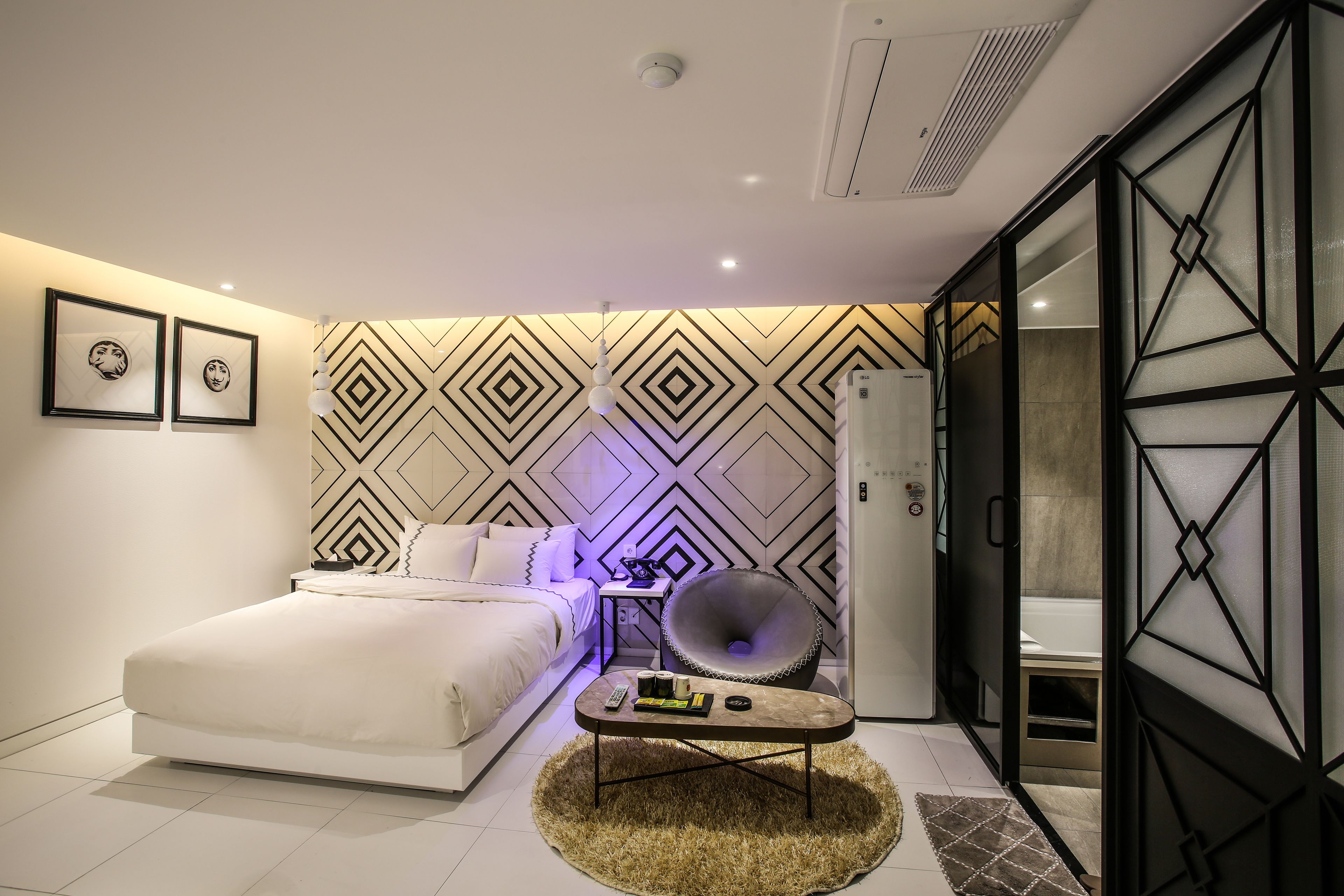 Quarto moderno com cama, mesa de cabeceira e uma cadeira.